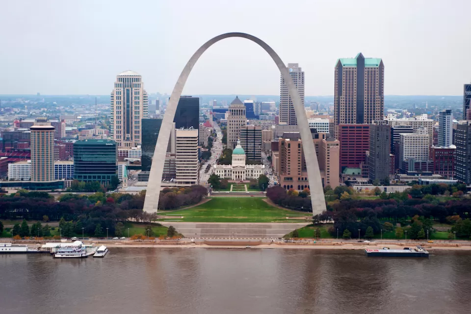 View of the Gateway Arch with Mississippi River in foreground and St. Louis skyline in background.